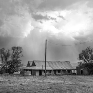 black and white photo of a storm in a rural setting with an old farmhouse